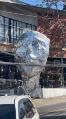 Mirrored human head sculpture spotted on city sidewalk