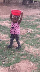 Toddler carries basin on head along dirt path in Akwanga