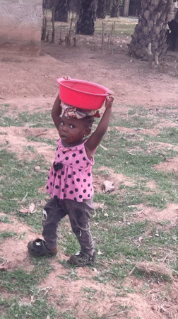Toddler carries basin on head along dirt path in Akwanga