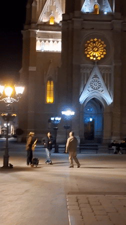 Street musician performs at illuminated Novi Sad church