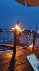 Fire performance and swimming at a waterfront pier at dusk