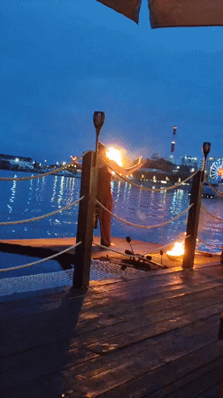 Fire performance and swimming at a waterfront pier at dusk