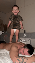 Toddler jumps on father's back during domestic playtime in Russia
