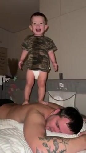 Toddler jumps on father's back during domestic playtime in Russia