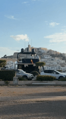 Black yacht docked in Ibiza's port on a clear afternoon