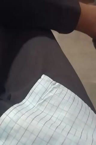 The video shows a close-up view of a person's legs and torso, wearing dark pants. A white checkered fabric is visible on the lower right side of the frame, tucked into the pants. The lighting creates shadows on the pants, suggesting the person is seated. There is no other information available about the scene.