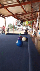 Men play casual pool game under covered outdoor area