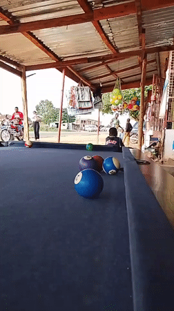 Men play casual pool game under covered outdoor area