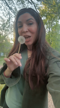 Woman collects dandelions in Kryvyi Rih park during spring afternoon