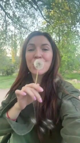 Woman collects dandelions in Kryvyi Rih park during spring afternoon