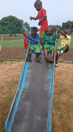 Children play on playground slide during morning hours