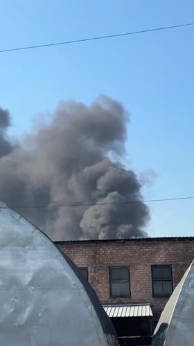 Heavy smoke rising behind a brick building in Bishkek