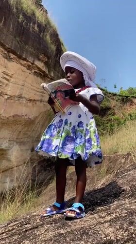 Girl reads book on rocky terrain in Amaseri, Nigeria