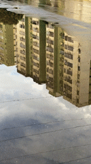 Apartment buildings reflected in puddle captured in Ciudad Guayana