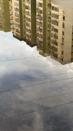 Apartment buildings reflected in puddle captured in Ciudad Guayana
