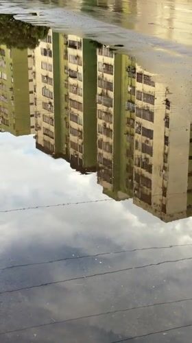 Apartment buildings reflected in puddle captured in Ciudad Guayana