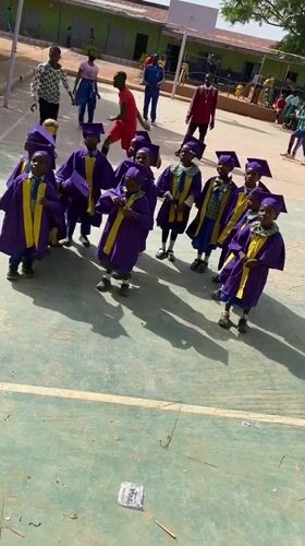 Children celebrate graduation ceremony on basketball court in Nigeria