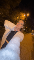 Woman walks brick sidewalk at night in Klin, Russia