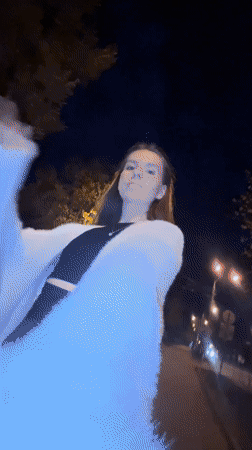 Woman walks brick sidewalk at night in Klin, Russia