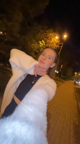 Woman walks brick sidewalk at night in Klin, Russia