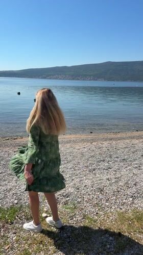 Woman dances on pebble beach in Bijela, Montenegro