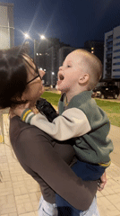 Woman holds child outside apartment building in Perm