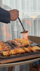 Person in suit flame-cooks shrimp on stone grills