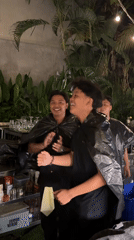 Bartenders pose with makeshift capes at outdoor bar in Kuta