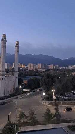 Illuminated mosque anchors Almaty skyline at dusk