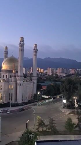Illuminated mosque anchors Almaty skyline at dusk