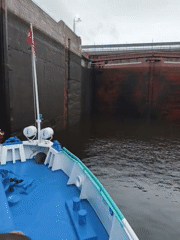 Boat group navigates a large canal lock on a grey day