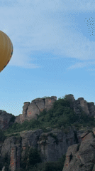 Yellow striped hot air balloon spotted over rocky mountains