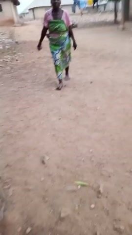 The camera moves across a dirt ground showing a woman walking away in the first second, and then points at the dusty ground before showing houses in the distance. The statement "we finished today" is spoken.