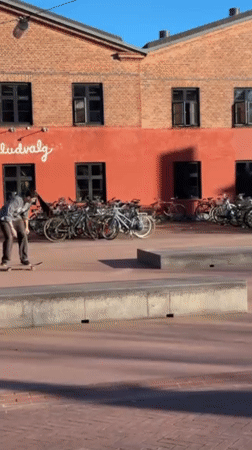 Skateboarders practice tricks in Copenhagen plaza on sunny afternoon