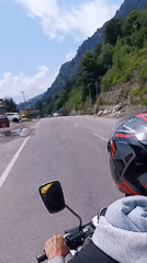 First-person motorcycle ride along a tree-lined road in Kalath