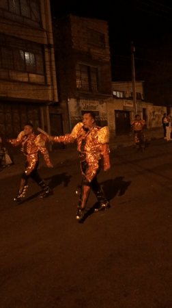 Ornate gold and red costumes light up a La Paz street at night