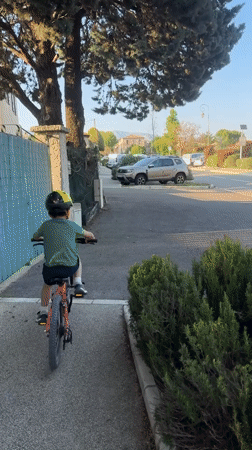 Child rides red bicycle in Rousset, France