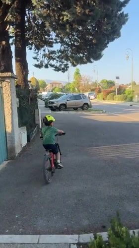 Child rides red bicycle in Rousset, France