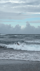 Three men play in ocean waves at North Kuta beach