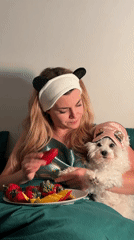 Woman in panda headband holds dog, strawberry in Budva