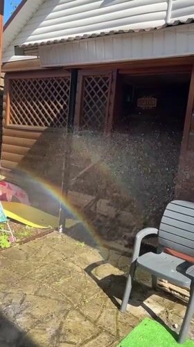 Toddler plays in backyard sprinkler creating rainbows in Nizhny Novgorod