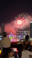 Families watch fireworks from Da Nang rooftops over rainbow bridge