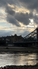Dresden bridge at sunset, Elbe River glowing under cloudy skies