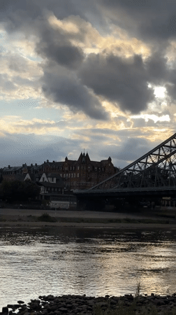 Dresden bridge at sunset, Elbe River glowing under cloudy skies