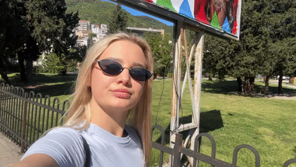 Woman films selfie videos while walking through sunny Budva