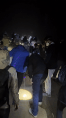 Group walks through foggy darkness with lights in Indonesia