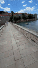 Couple walks stone bridge to Sveti Stefan island Montenegro