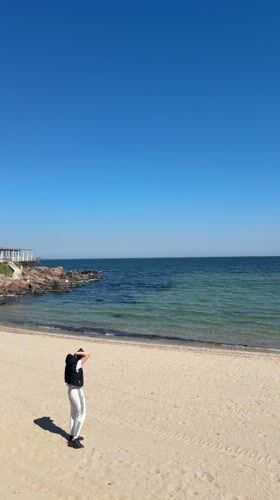 Person stands on sunny Sozopol beach under clear skies