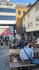 Londoners enjoy sunny afternoon socializing at outdoor pub garden