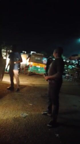 Nighttime street gathering with auto-rickshaws documented in Bukuru